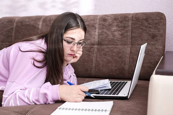 Студентка лежит на диване и смотрит на ноутбук — стоковое фото