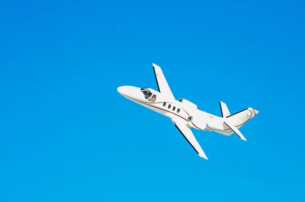 Um avião privado branco voa no céu azul — Fotografia de Stock