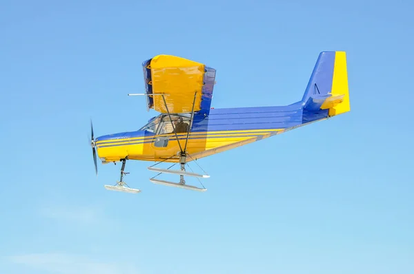 Um plano amarelo com uma hélice no céu azul — Fotografia de Stock