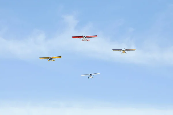 Dört küçük uçaklar kırmızı, sarı ve beyaz renklerde gökyüzünde uçmak. — Stok fotoğraf