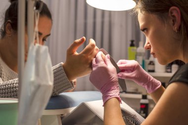 Tırnak salonu istemci manikürcü eldiven çivi törpü ile işleme