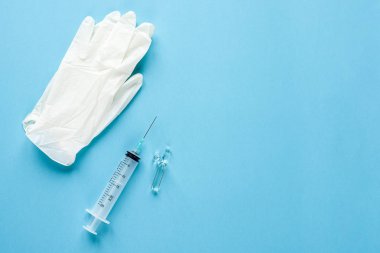 Tıbbi tek kullanımlık şırınga, ampul, eldiven mavi bir arka plan üzerinde