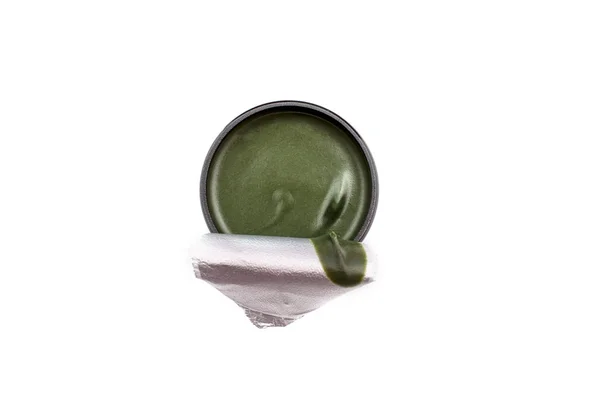 Green body and face cream in round package, top view, isolated on white