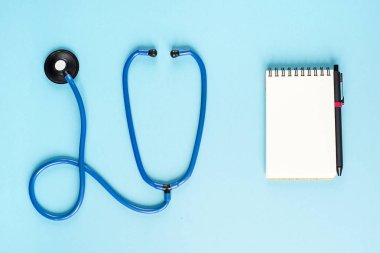 Mavi stetoskop ve mavi bir arka plan üzerine bir not defteri