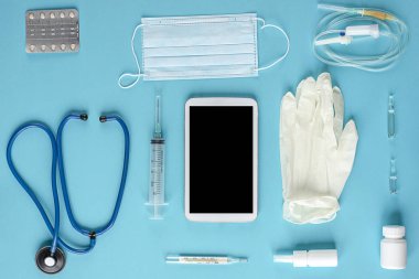 Çeşitli tıbbi malzeme ve tablet üzerinde mavi arka plan