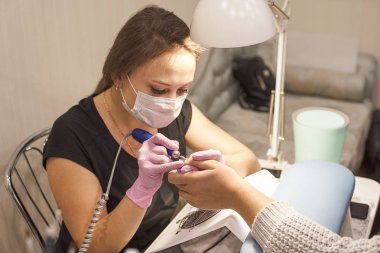 Belgili tanımlık tırnak salonu istemci manikürcü pembe eldiven vernik manikür aygıtla kaldırır