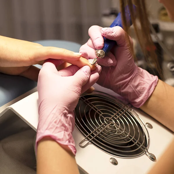 Im Nagelstudio Maniküre-Kundin in rosa Handschuhen entfernt Lack mit Maniküre-Gerät — Stockfoto