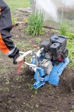 Genç adam bir motor bloğu yardımıyla toprakla pulluklar