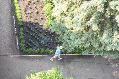 Bilinmeyen bir adam bir hortum ile çiçek Bahçe sulama