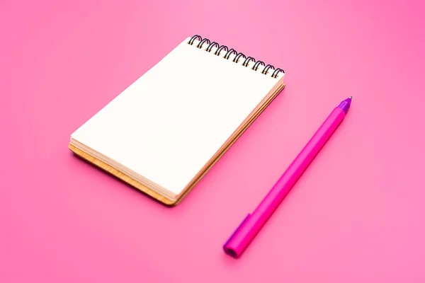 Blank notebook with spiral for the application of labels and pen on pink background — Stock Photo, Image