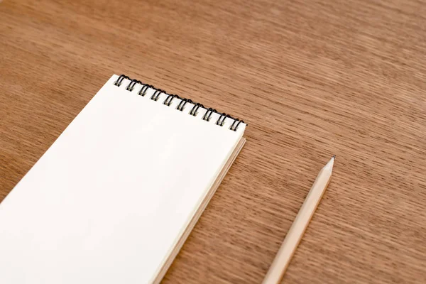 Caderno em branco com espiral para a aplicação de etiquetas e caneta em fundo de madeira — Fotografia de Stock