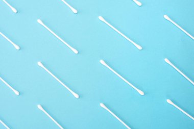 Üst üste mavi bir arka plan üzerinde beyaz pamuk tomurcukları yalan.