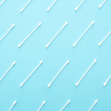 Üst üste mavi bir arka plan üzerinde beyaz pamuk tomurcukları yalan.