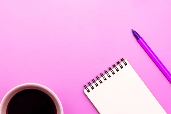 Caderno em branco com espiral para a aplicação de rótulos, café e caneta sobre fundo rosa — Fotografia de Stock