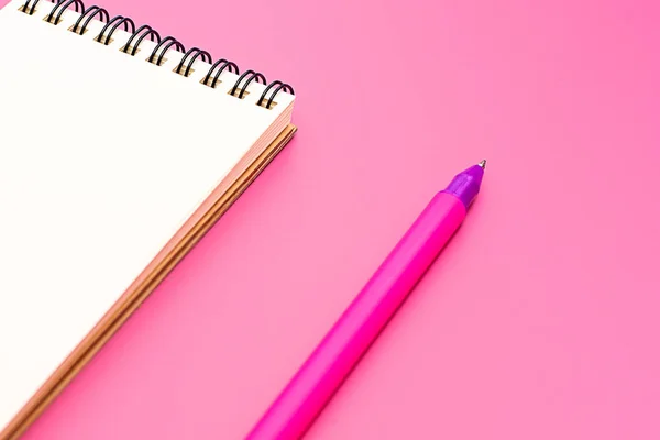 Caderno em branco com espiral para a aplicação de etiquetas e caneta sobre fundo rosa — Fotografia de Stock