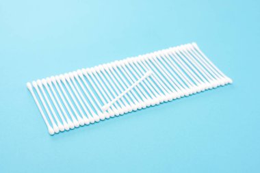 Üst üste mavi bir arka plan üzerinde beyaz pamuk tomurcukları yalan.