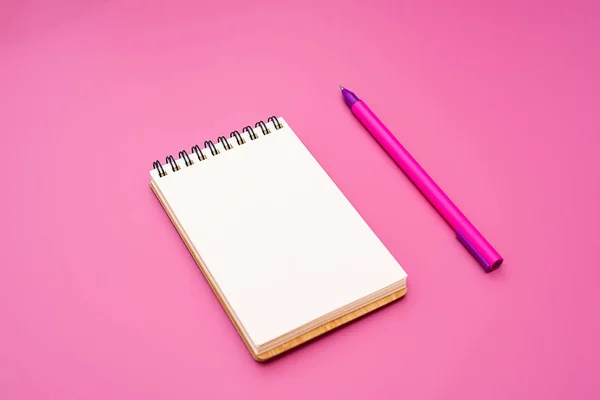 Caderno em branco com espiral para a aplicação de etiquetas e caneta sobre fundo rosa — Fotografia de Stock