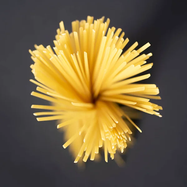 Surowe żółte płaskie spaghetti na czarnym tle w postaci kwiatu . — Zdjęcie stockowe