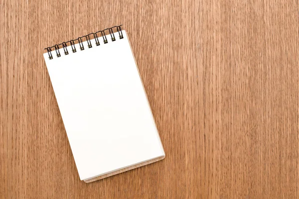 Caderno em branco com espiral para a aplicação de etiquetas em fundo de madeira — Fotografia de Stock