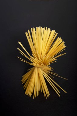 Bir çiçek şeklinde siyah bir arka planda ham sarı düz spagetti .