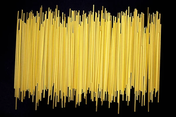 Obehandlad platta spaghetti på svart bakgrund — Stockfoto