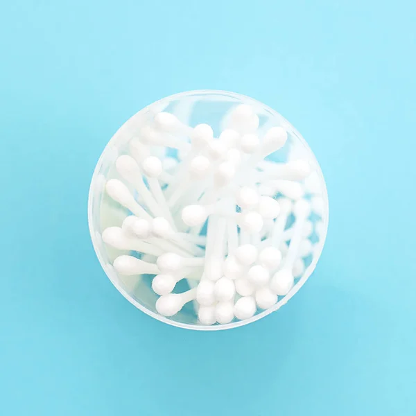 White cotton swabs are in a jar on a blue background. Means of hygiene.