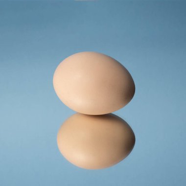 Bir kahverengi yumurta ve bir mavi arka planı yansıtmadaki onun yansıması .