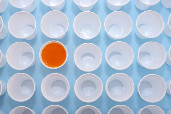 Bicchieri vuoti bianchi di plastica usa e getta e un bicchiere pieno di limonata arancione — Foto Stock