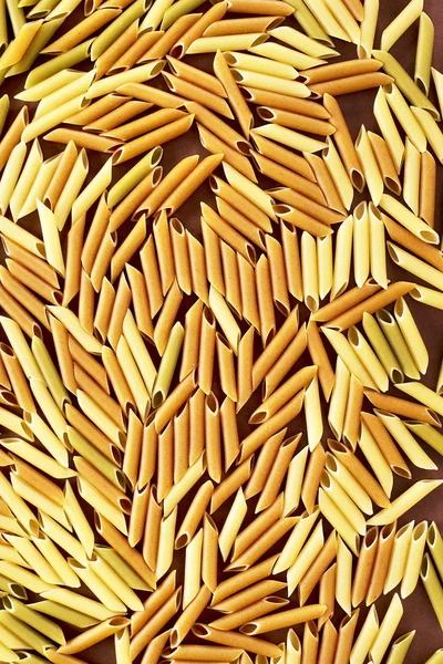 Különböző tészták barna, sárga és zöld színű csövek formájában — Stock Fotó