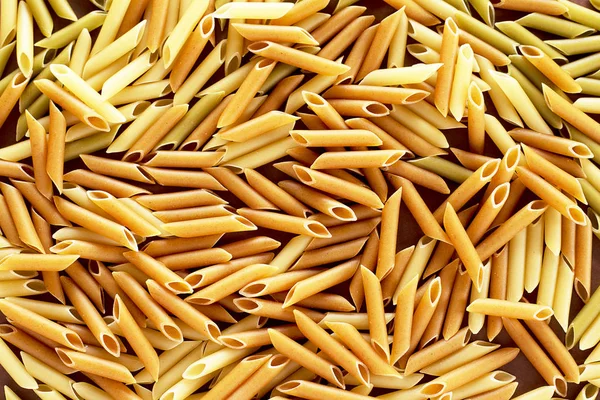 Verschillende pasta 's in de vorm van buizen van bruine, gele en groene kleuren — Stockfoto