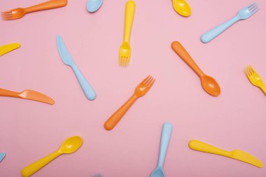 Renkli plastik sofra : çatal, bıçak ve kaşık pembe arka plan üzerinde.
