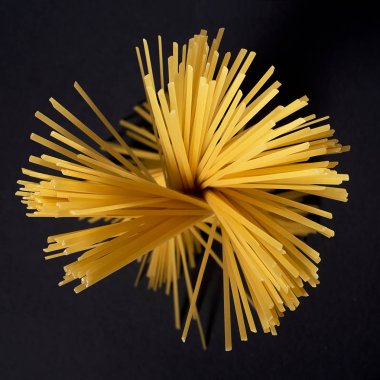 Bir çiçek şeklinde siyah bir arka planda ham sarı düz spagetti .