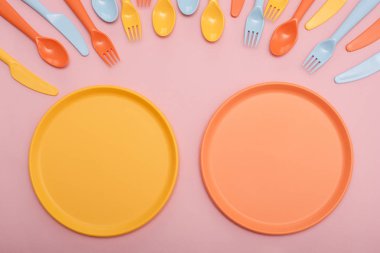 Renkli sofra : kaşık, bıçak, çatal ve pembe arka plan üzerinde iki plaka sarı ve turuncu renk