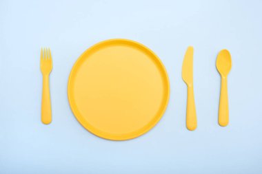 Sofra sarısı renk: plaka, bıçak, mavi arka plan üzerinde çatal