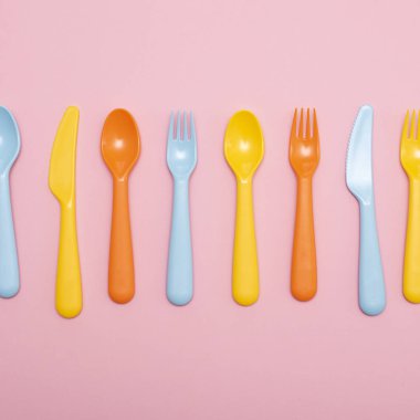 Renkli sofra : pembe arka plan üzerinde aralığında kaşık, bıçak, çatal.