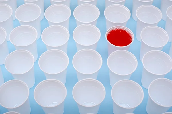 Vasos vacíos blancos de plástico desechables y un vaso lleno de limonada roja — Foto de Stock