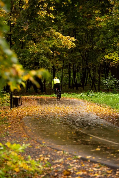 Ποδηλασία σε πολύχρωμο φθινοπωρινό πάρκο κατά τη διάρκεια της βροχής — Φωτογραφία Αρχείου