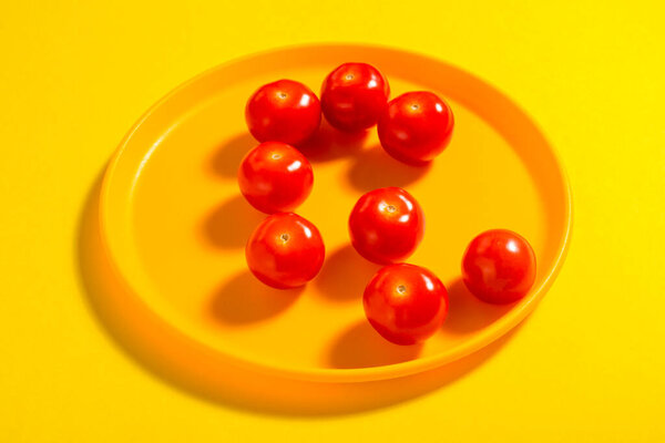 Cherry tomato on yellow plate. Concept. Vegetable. Shadow.