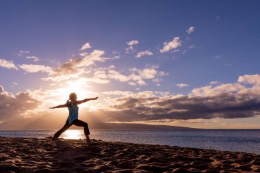 pratik yoga gün batımında Maui kumsalda bir kadın
