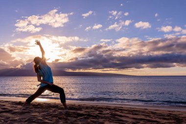 pratik yoga gün batımında Maui kumsalda bir kadın