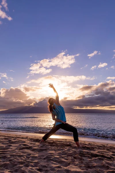 pratik yoga gün batımında Maui kumsalda bir kadın