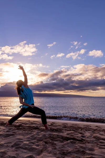 pratik yoga gün batımında Maui kumsalda bir kadın