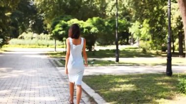       Güzel genç kız dönüş ve güneş yaz Park gülümsüyor. Ağır çekim