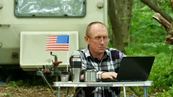 美国男子旅行者工作在笔记本电脑附近的拖车露营和思考 自由职业者的生活 — 图库视频影像