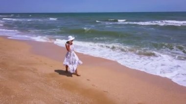 4k hava. Yaz plaj yürüyen ince kadın elbise ve şapka, sinek.