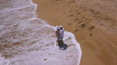    4k hava. Sevgi dolu çift okyanus kıyı şeridi üzerinde yürür. Adam kadın kucaklayan ve yürür