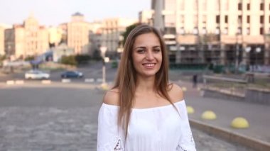 Genç güzel kadın stand ve gülümseme şehirdeki sokak. 