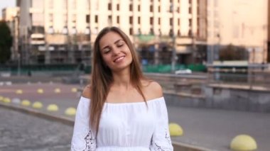  Beyaz elbiseli Genç kadın yürümek ve sabah şehirde sokak gülümse. Sürekli çekim