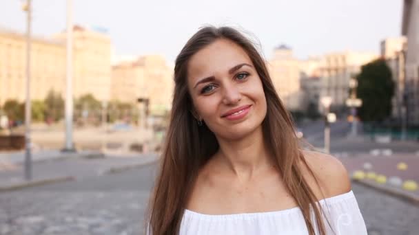 若い女性のスタンドと街の通りに笑顔ぼやけて背景建物 — ストック動画