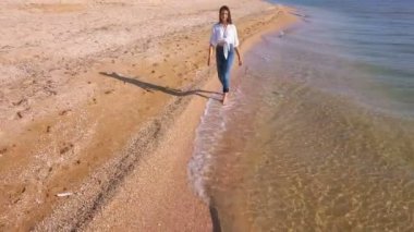 4k hava. Genç ince kız Genç okyanus ya da deniz sahilde yürümek. Önden görünüm